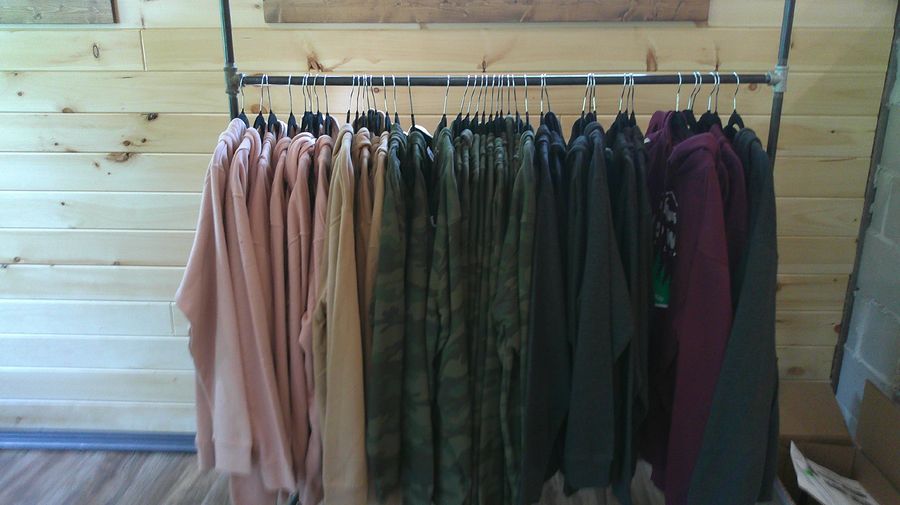 Full merch rack at Midway General Store — hoodies, tees, camo